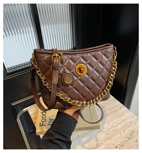 Close-up of brown quilted bag with gold twist lock and metallic chain detail