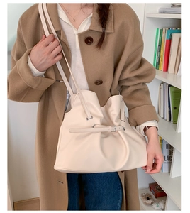 Detail showing creamy white pleated tote bag with strap buckle on a casual outfit