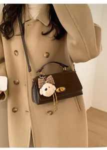 Detail of vintage dark brown suede handbag featuring a gold buckle and cute puppy charm