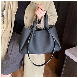 Detail of black lychee grain tote bag with dual handles and metal rivets for commuting