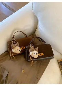 Detail of elegant two-tone shoulder bags featuring gold oval twist locks and bear charms