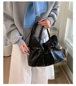 Detail of black pleated tote bag with silver eyelets and soft glossy texture material
