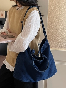 Grand sac cabas en jean bleu foncé avec bandoulière présenté dans un cadre décontracté