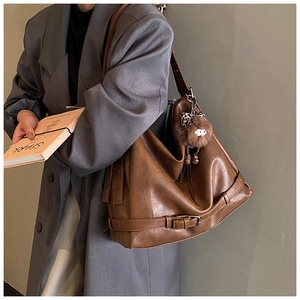 Brown large capacity tote bag with decorative buckle and plush charm on a model