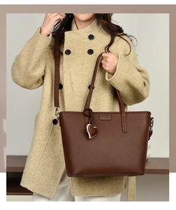Close-up of dark brown lychee texture tote bag featuring a heart charm and brand logo