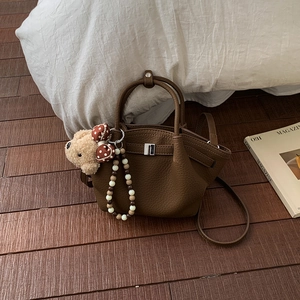 Detail of brown litchi pattern leather bag with plush bear charm and beaded strap