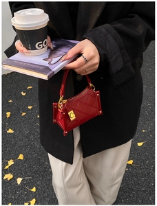 Street style shot of red quilted micro bag with gold hardware and seasonal city background