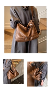 Close-up of brown faux leather shoulder bag featuring metal buckle straps and plush charm