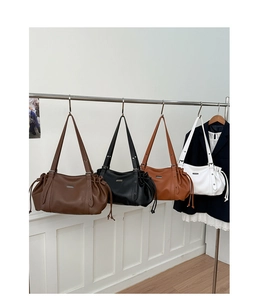 Detail of four retro leather tote bags in brown, black, tan, and white with drawstrings