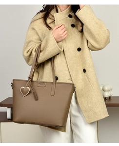 Brown litchi grain tote bag with heart charm shown on beige coat outfit for women