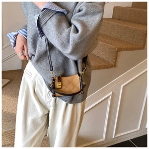Close-up of quilted brown leather handbag featuring a gold square twist lock and strap