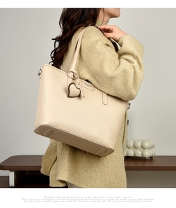 Detail of beige lychee pattern leather tote bag with heart charm on a model
