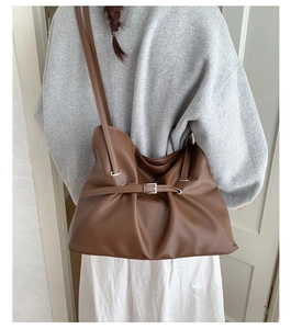 Detail of pleated dark brown soft leather tote bag showing texture and silver metal buckle