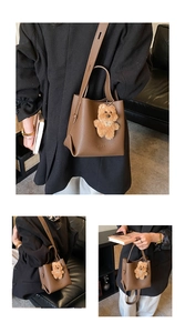Detail of dark brown pebble leather bucket bag featuring a plush bear charm and long strap