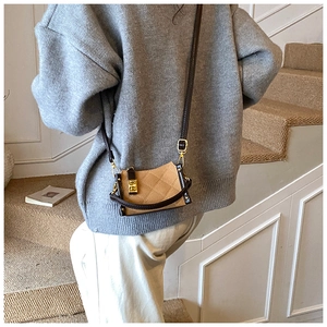 Detail of a khaki quilted mini bag featuring a gold buckle and vintage leather trim