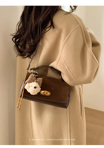 Detail of retro suede crossbody bag with gold twist lock and cute bear charm accessory