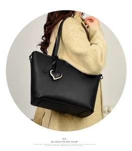 Close-up of black leather tote bag with lychee texture and heart-shaped pendant detail