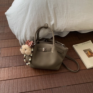 Detailed view of lychee pattern leather bag with plush bear charm and metal buckle