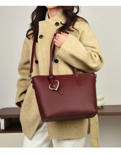 Macro view of burgundy pebble leather tote bag featuring elegant heart charm detail