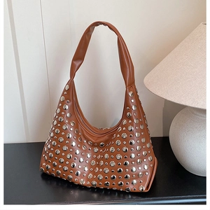 Macro detail of brown leather crescent bag featuring metallic silver stud decorations