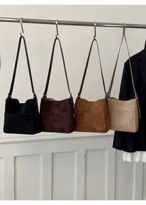 Gros plan de sacs seaux en daim en quatre couleurs suspendus sur un portant