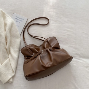 Detail view of deep brown ruched leather shoulder bag with silver buckle and soft texture