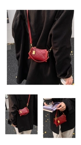 Detailed close-up of a small burgundy quilted leather crossbody bag with golden clasp