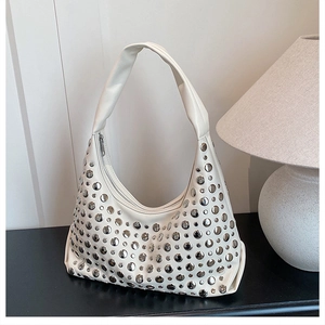 Close-up of cream hobo bag featuring silver metal studs and wide shoulder strap detail