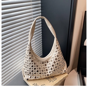 Detailed view of beige hobo bag with polished silver metal studs and wide shoulder strap
