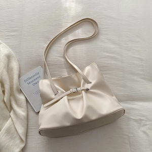 Detail shot of a cream pleated tote bag featuring delicate straps and metal buckles
