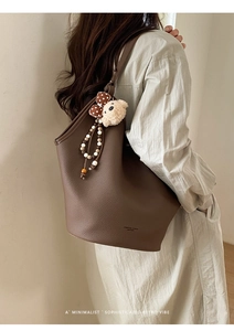 Détail du sac seau en cuir litchi marron avec pendentif ours et poignée en perles
