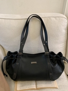 Retro black lychee textured tote bag with drawstring closure on a beige sofa