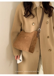 Gros plan sur un sac bandoulière en daim marron porté avec un manteau au style rétro