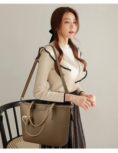 Deep brown tote bag with pebble leather texture and heart charm shown in use