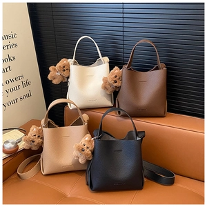 Detail view of lychee pattern leather bucket bags with plush bear charms in four colors