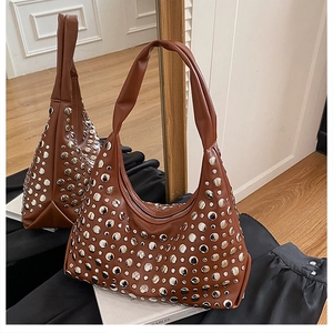 Close-up of brown hobo bag with silver metal rivets and stylish wrinkled shoulder strap
