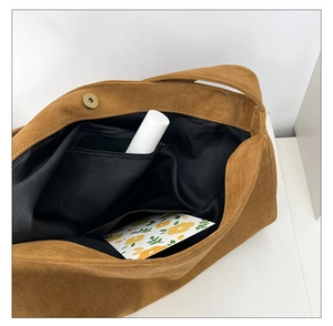 Vue intérieure du sac en daim marron montrant la grande capacité et la poche zippée
