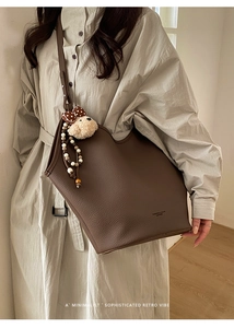Détail d'un grand sac cabas en cuir grainé marron avec charm ours sur le mannequin