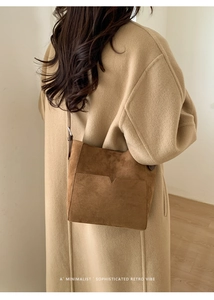 Vue détaillée du sac seau en daim marron avec bandoulière réglable porté par un mannequin