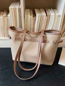Sac cabas minimaliste en cuir beige avec finitions marron sur un bureau en bois