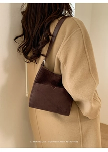 Gros plan d'un sac seau rétro en daim marron avec bandoulière sur un manteau en laine