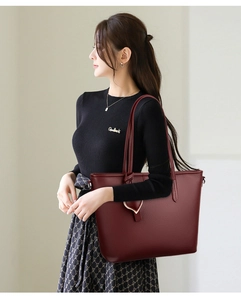 Detailed side view of large burgundy tote bag in lychee leather worn by a model