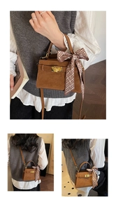 Detail of a brown suede trapezoid handbag with gold clasp and decorative silk scarf