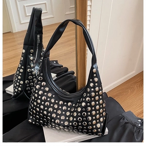 Detail of black faux leather hobo bag featuring silver metal studs in a lifestyle setting