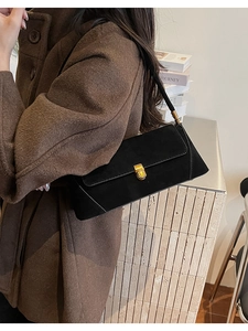 Dettaglio della borsa sottobraccio in camoscio nero con fibbia dorata sul modello