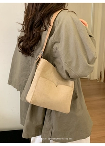 Détails de vue latérale du sac seau minimaliste en daim avoine avec une poche en forme de V