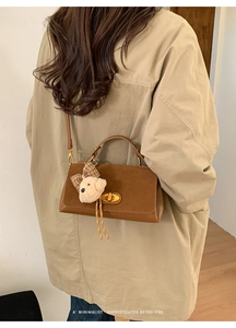 Close-up of brown suede and leather patchwork bag with a cute plush puppy pendant