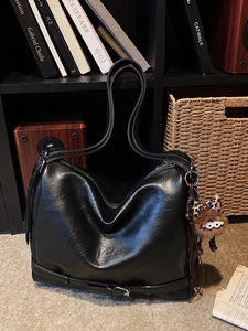 Large black retro motor-style shoulder bag with fuzzy monster charm and bow detail
