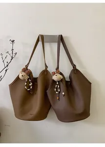 Détail de sacs seaux en cuir grainé avec un pendentif d'ours charmant et vintage