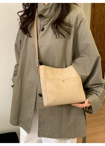 Gros plan du sac seau en daim beige minimaliste avec design de poche rétro en V
